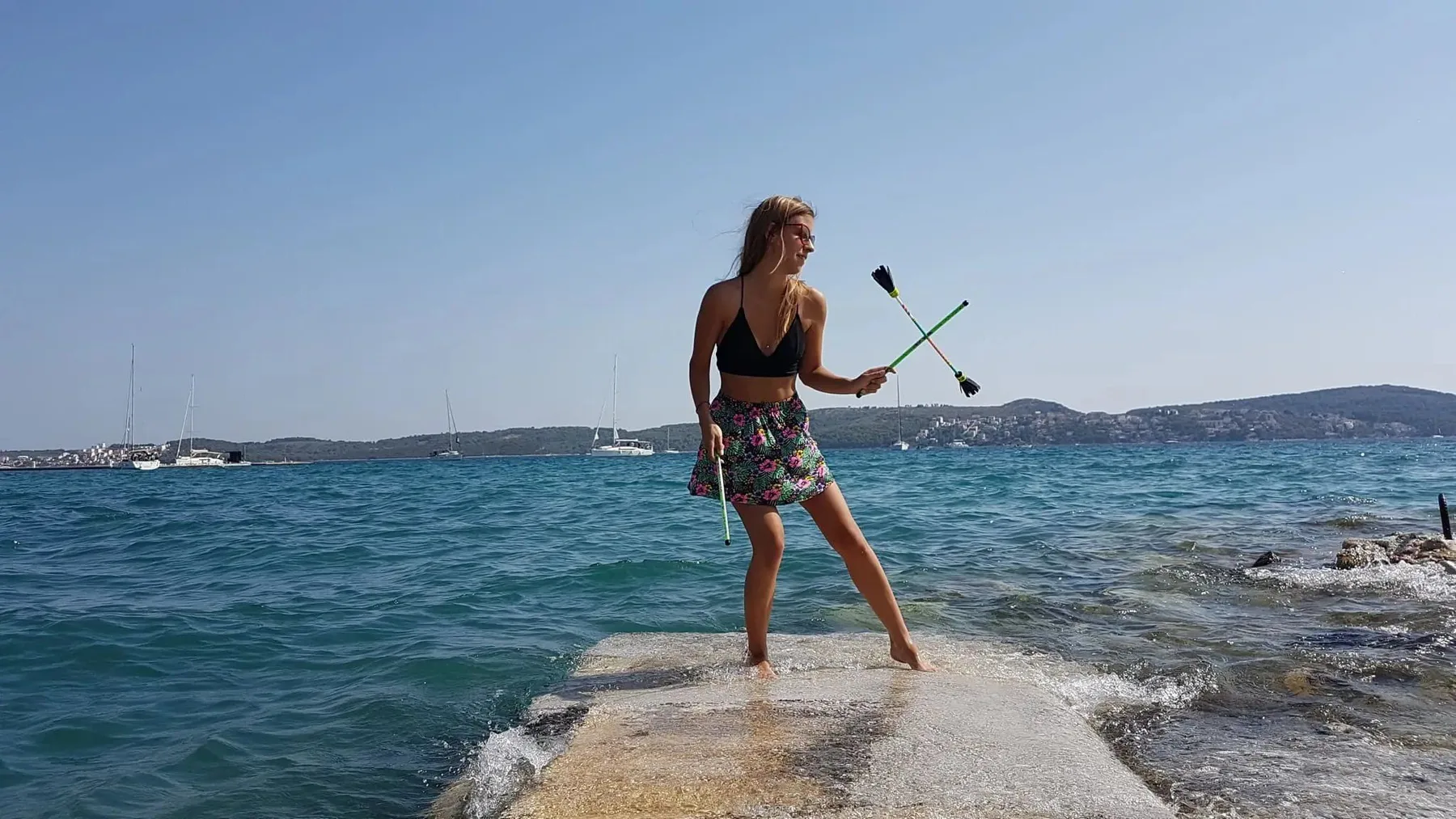 Mädchen spielt mit einem Flowerstick auf einem Steg am Meer